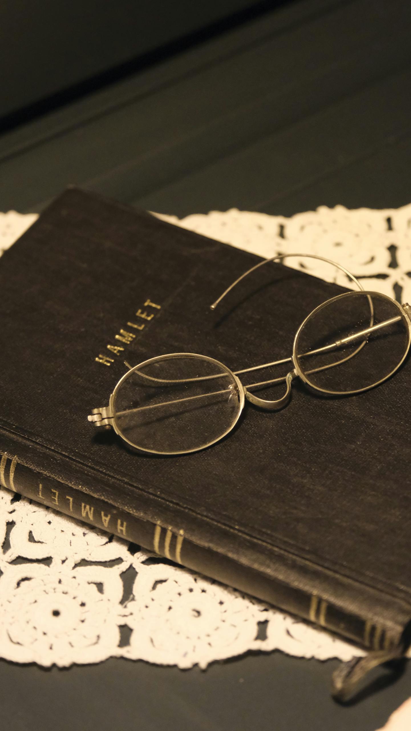 Antique glasses resting on a vintage edition of Hamlet, evoking a timeless literary feel.